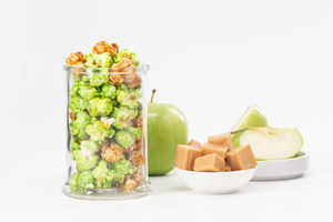 Mouthwatering Caramel Corn and fresh green Apple Popcorn displayed in glass with apple slices and caramel candies