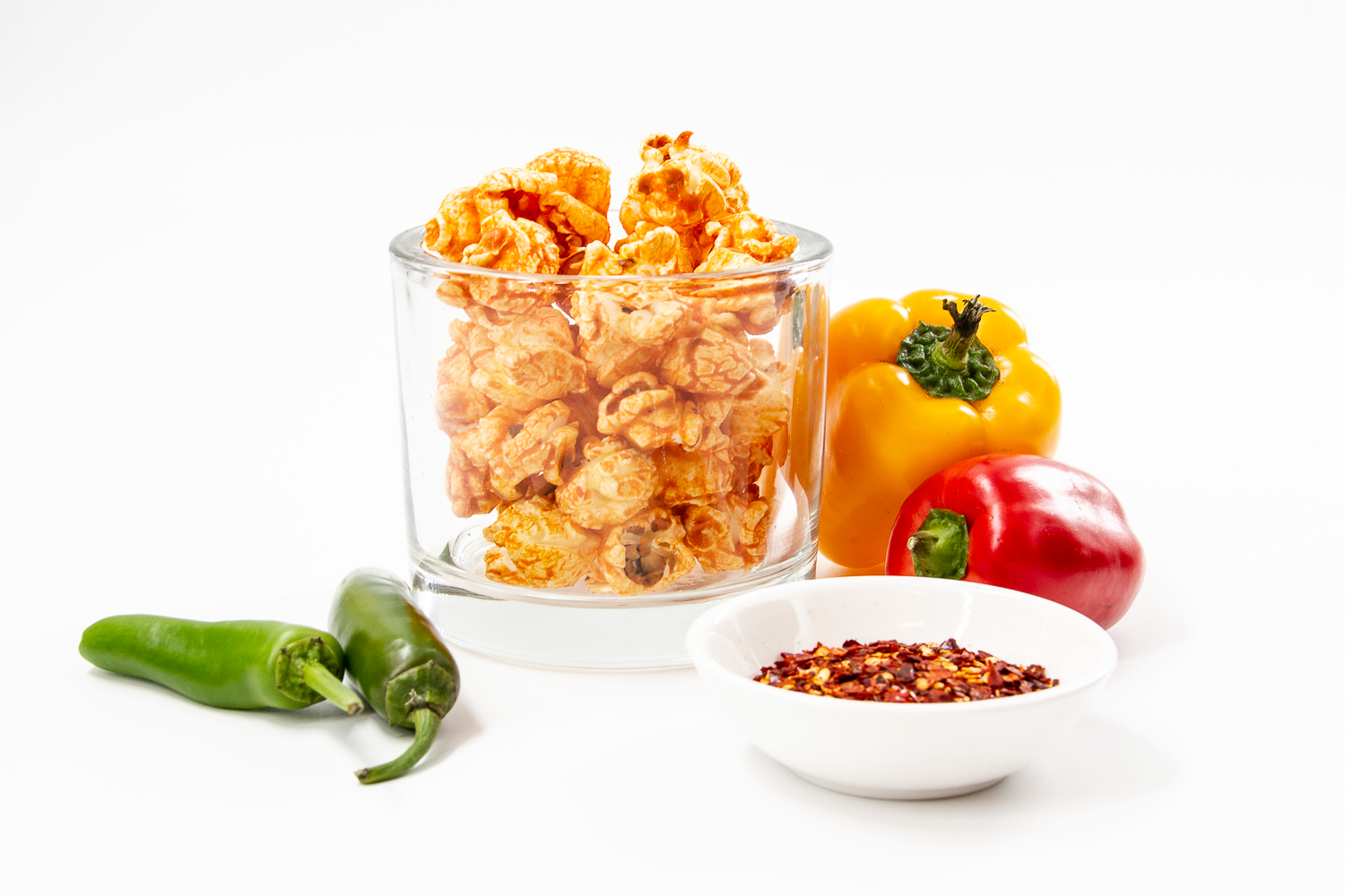 Hot & Spicy Gourmet Popcorn displayed in cup with red pepper, yellow pepper, jalapeno and spices