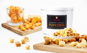 assorted flavors of caramel, cheese and white cheddar gourmet popcorn displayed with a white 2 gallon gift tin.